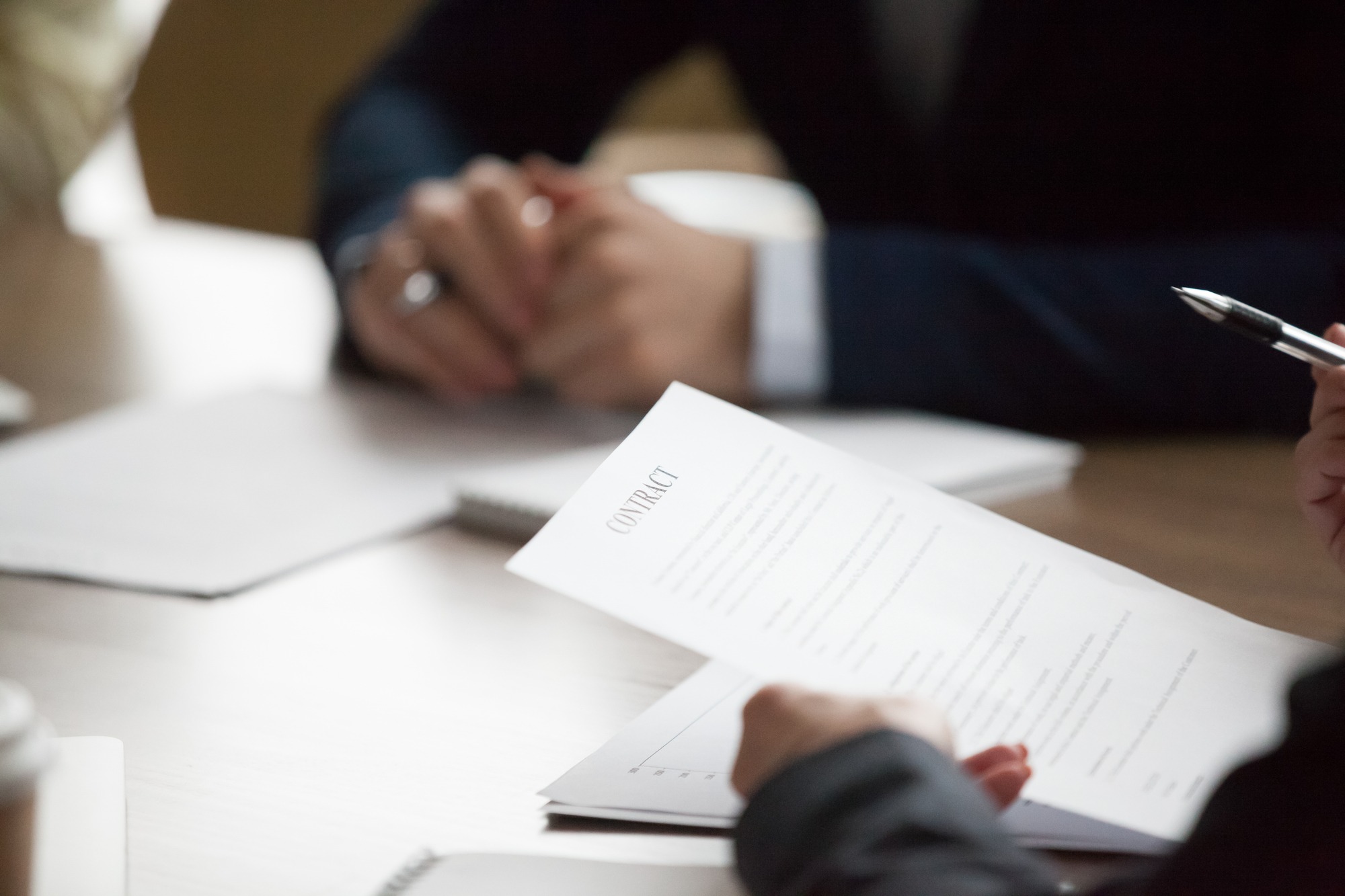 Businesspeople sitting office desk at meeting. Woman ceo holding pen and contract, ready to sign document, close up. Client, customer lease agreement buy sell real estate. Successful deal, hr concept