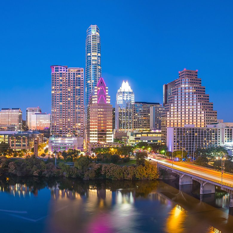 A panoramic view of the Austin skyline, showcasing the city's modern architecture against a clear blue sky.